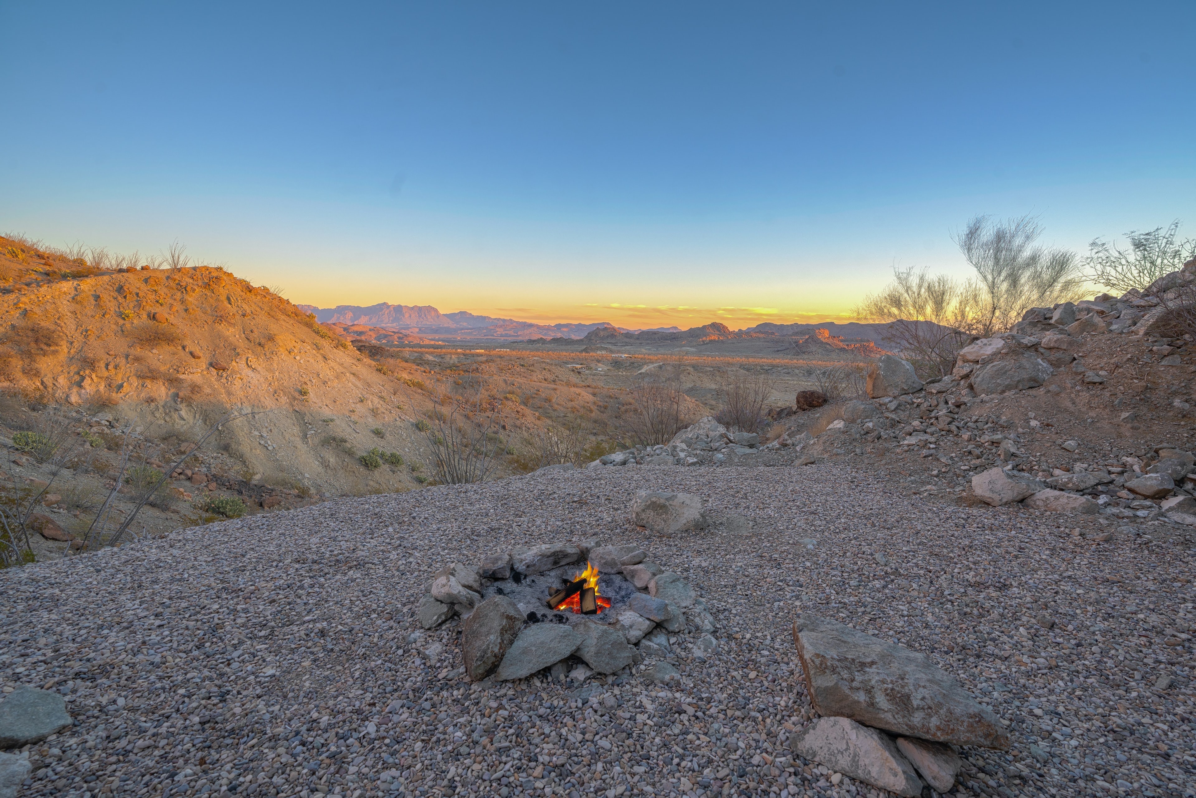 Campfire burning in desert landscape at sunset